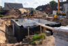Baugrube mit weißen Betonwänden und schwarzer Abdichtung beim Hausbau in Wohnsiedlung