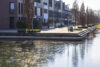 Moderne Wasserlandschaft mit Promenade, Wohnbauten aus Backstein und Glas sowie Herbstbäumen am Flussufer